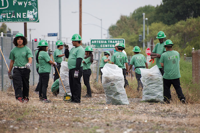 Members of the L.A. Conservation Corp clear brush and debris from a patch of land near Vermont Avenue and Artesia Boulevard.