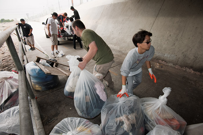 Crews load a pickup with bags of trash to take to a waiting dumpster.