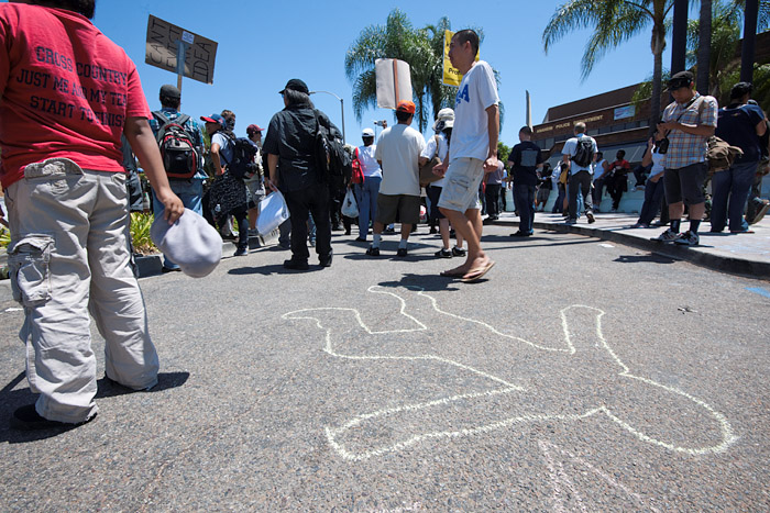 Demonstrators stand near a chalk outline in front of the Anaheim Police Department.